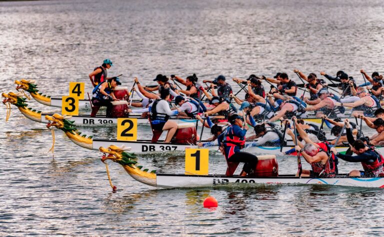 2 dragon boats with each team of dragon boaters paddling fiercely head to head